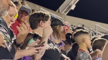 Orlando, Florida, ABD - 03.02.2024: Seyirciler odaklanmış ve duygusal ifadelerin yer aldığı canlı bir stadyum etkinliği izliyor. İnsanlar harekete seyirciler arasında yan yana oturarak tepki veriyorlar..