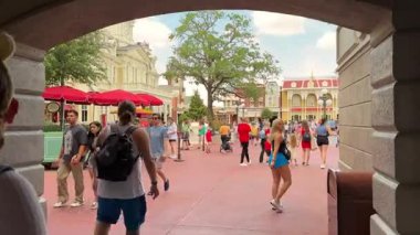 Orlando, Florida, ABD - 05.06.2024: Ziyaretçiler Macera Parkı 'nın giriş alanından geçtiler. İnsanlar renkli binalar ve park yerleriyle çevrili güneşli bir günün tadını çıkarıyorlar..
