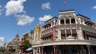 Orlando, Florida, ABD - 05.06.2024: Viktorya tarzı binalar Walt Disney World 'deki Magic Kingdom' da ABD 'nin ana caddesi. Misafirler güneşli mavi gökyüzünün altında tente ve mağazaların önünde yürüyorlar..