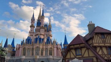 Orlando, Florida, ABD - 05.06.2024: Külkedisi Kalesi 'nin pembe ve mavi kuleleri Disneys Magic Kingdom' da parlak bir gökyüzüne karşı yükseliyor. Detaylı gotik mimari ve altın aksanlar ikonik bir Fantasyland yaratıyor..