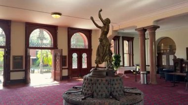 Büyük bir lobide bronz bir heykel, kırmızı halı ve süslü ahşap işçiliği yer alır. Kemerli kapılar, sütunlar ve gün ışığı zarif bir tarihi iç mekan yaratır..