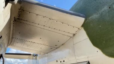 Eski bir askeri uçağın yakından bakınca kuyruk ve kanat panelleri perçin sıralarıyla görünüyor. Metal uçak iskeleti ve kamuflaj boyası klasik uçak yapımını ön plana çıkarıyor..
