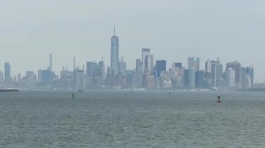 Manhattan silueti New York Limanı 'nın üzerinde yükseliyor. Uzun gökdelenler ve ofis kuleleri su üzerinde yoğun bir şehir manzarası yaratıyor..