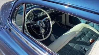 Orlando, Florida, ABD - 02.03.2024: Yakından bakınca, beyaz direksiyon ve krom gösterge paneli olan mavi klasik bir araba görünüyor. Yastıklı bank koltuğu ve klasik detaylar eski, el değmemiş bir görünüm yaratır..