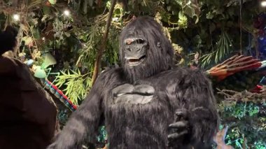 Zengin orman temalı bir restoranda büyük bir goril heykeli duruyor. Yapay yeşillik ve dramatik ışıklandırma eğlenceli bir yağmur ormanı hayvan sahnesi yaratır..