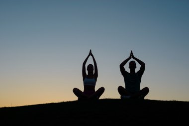 Boy and girl meditating at sunset.