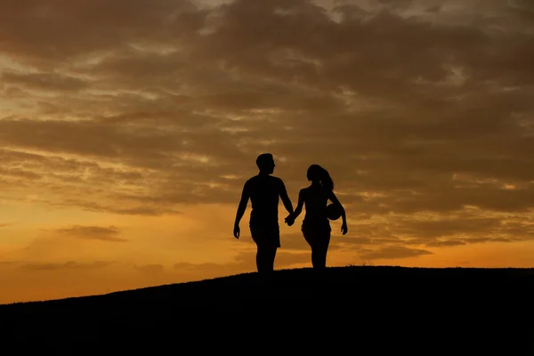 Älskande par sportsmen promenad på kvällen kullarna. — Stockfoto