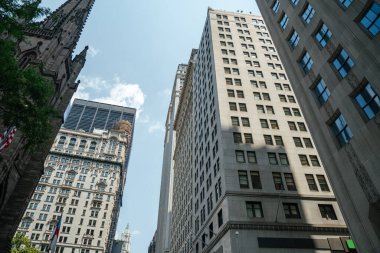 Manhattan Finansal Bölgesi 'nde tarihi bir kilisenin yanında gökdelenler yükseliyor. Görüntü, modern iş kuleleri ve eski mimari arasındaki zıtlığı yakalıyor..