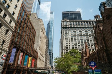 New York, New York, New York, ABD - 08.01.2024: New York 'taki Wall Street modern gökdelenler ve tarihi binaların çarpıcı bir karışımını sergiliyor. Trinity Kilisesi cam kulelerin ve klasik cephelerin yanında duruyor..