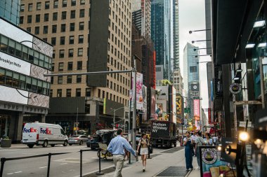 New York City, New York, ABD - 08.01.2024: New York City 'deki Times Meydanı' nın canlı bir görüntüsü, kaldırım boyunca yürüyen insanları ve FedEx gibi araçları ve yoldaki dağıtım kamyonlarını gösteriyor. Parlak reklam panoları ve yüksek binalar canlı bir şehir yaratıyor.