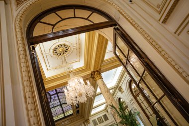 Açık kemerli kapı aralığı, kristal avize, vitray pencere ve dekoratif tavan tasarımının yer aldığı büyük bir balo salonunu gözler önüne seriyor. Lüks iç tasarımı klasik mimari unsurlar ve altın aksanlarla süslenmiş..