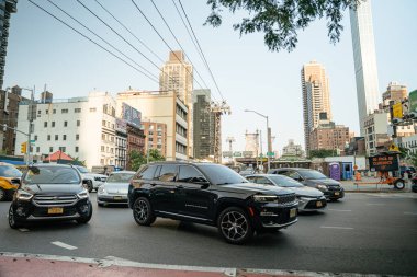 New York City, New York, ABD - 08.01.2024: Siyah bir SUV de dahil olmak üzere birden fazla araç yoğun bir New York kavşağında trafikte bekliyor. Queensboro Köprüsü ve çevresindeki yüksek binalar arka planda görünür..