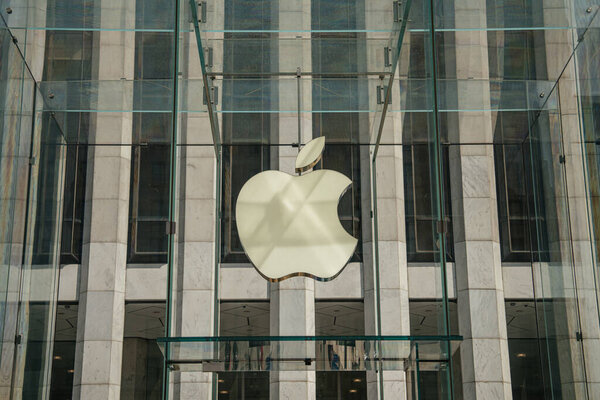 Нью-Йорк, Нью-Йорк, США - Крупный план культового стеклянного куба входа в Apple Store в Нью-Йорке. Большой логотип Apple подвешен внутри прозрачных стеклянных стен, отражающих современную элегантность бренда.