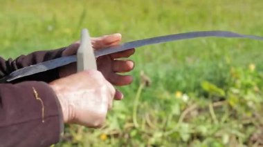 yaşlı adam onun tırpan keskinleştirme.