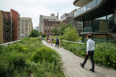 Ziyaretçiler, Manhattan 'da yeşillik ve çağdaş mimari ile çevrili High Line parkı boyunca yürüyorlar. Sahne, New York 'ta kentsel eğlence ve modern şehir tasarımını yakalıyor..