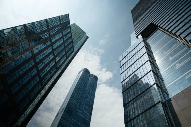 Manhattan, New York 'ta gökyüzüne yükselen yüksek cam gökdelenlerin dramatik alçak açılı görüntüsü. Modern mimari güçlü kentsel ufuk çizgisini tanımlar.