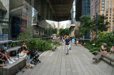 New York City, New York, ABD - 08.02.2024: Manhattan, New York 'taki modern binalar arasındaki High Line yüksek parkı boyunca dinlenen ve yürüyen ziyaretçiler. Kentsel yeşil alan mimari, eğlence ve turizmi birleştiriyor.