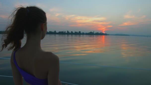Meisje genieten van de zonsondergang op de rivier. — Stockvideo