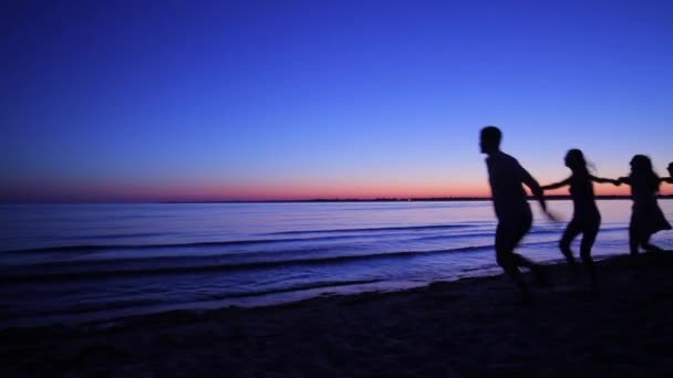 Young people running on the sea shore early in the morning. — Stockvideo