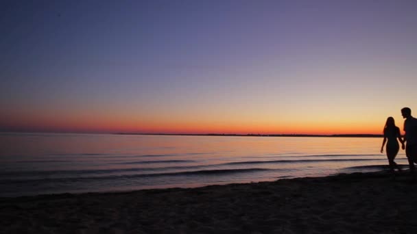 Kvällspromenad älskare längs stranden. — Stockvideo