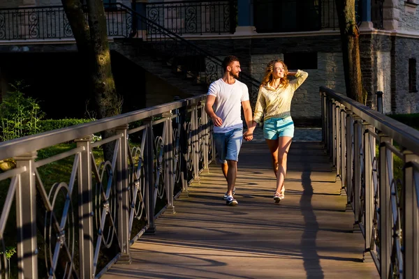 Aşık adam ve kız bir köprü parkta yürüyüş. — Stok fotoğraf
