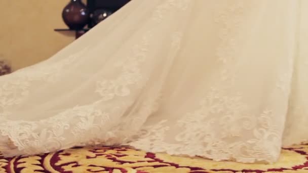 Lange pluim van de jurk van de bruid strekt zich uit het tapijt. — Stockvideo