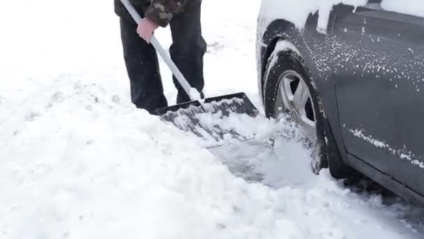 Man gräver ut sin bil från snön. — Stockvideo