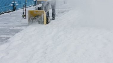 Kapıcı kar traktör temizler.