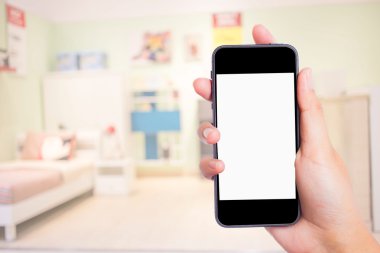 Arka plandaki yatak odasında cep telefonuyla fotoğraf çekiyor..