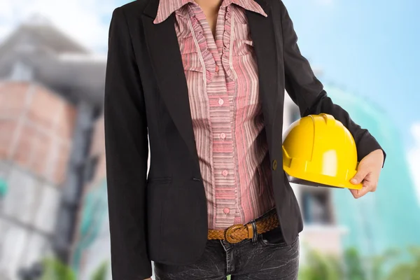 Engineer holding yellow helmet for workers security on backgroun