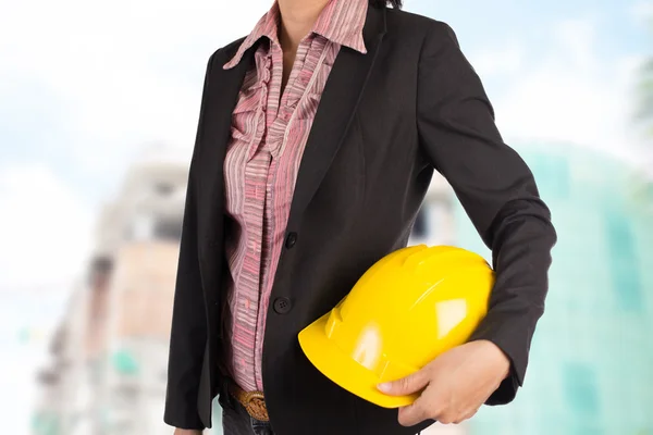 Engenheiro segurando capacete amarelo para a segurança dos trabalhadores no backgroun — Fotografia de Stock