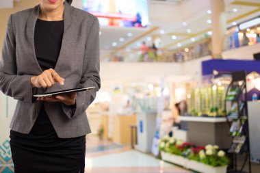Alışveriş merkezinde tablet kullanan kadın.