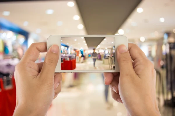 Kvinnan tar bilder på en mobiltelefon i köpcentrum. — Stockfoto