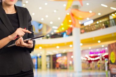 Alışveriş merkezinde dijital tablet kullanarak iş kadını.