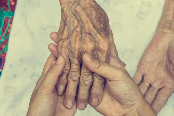 Hand van vrouw aanraken senior vrouw in kliniek. — Stockfoto