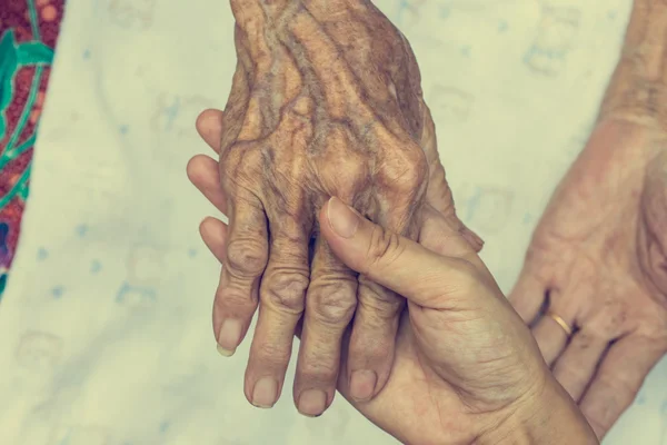 Hand van vrouw aanraken senior vrouw in de kliniek. Vintage filter — Stockfoto