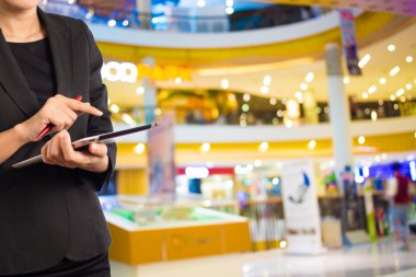 Alışveriş merkezinde dijital tablet kullanarak iş kadını.