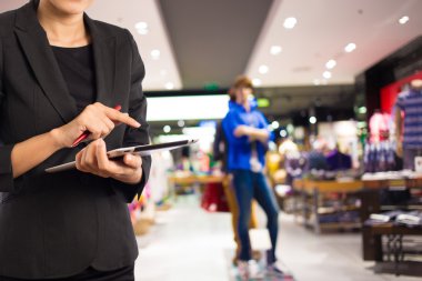 Alışveriş merkezinde dijital tablet kullanarak iş kadını.