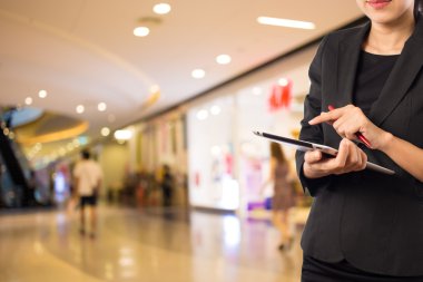 Alışveriş merkezinde dijital tablet kullanarak iş kadını.