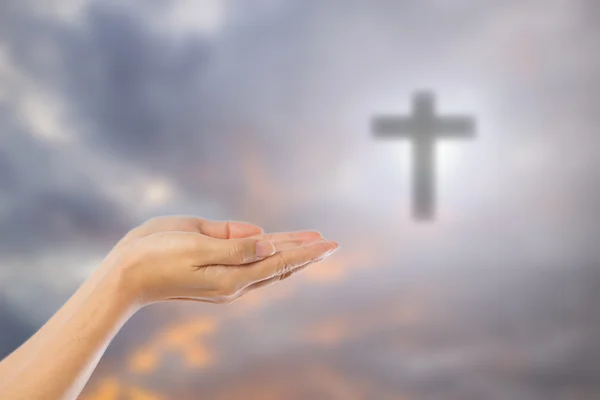 Mãos de homem orando sobre borrado a cruz no céu backgroun — Fotografia de Stock