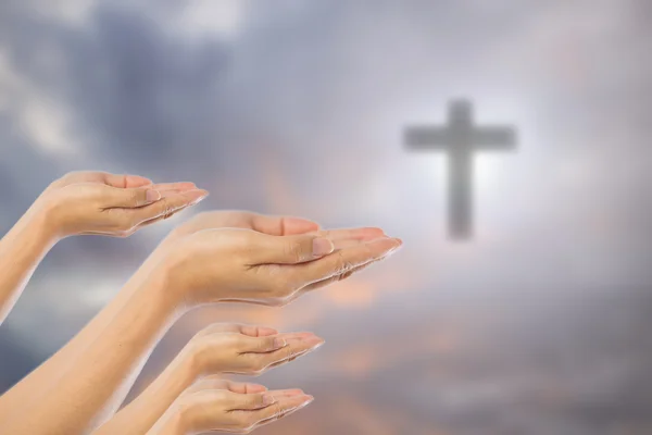 Manos de hombre rezando sobre borrosa la cruz en el cielo backgroun —  Fotos de Stock