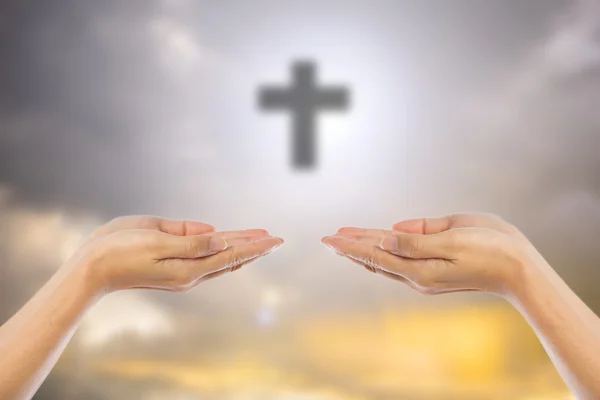 Hände eines betenden Mannes verschwimmen das Kreuz auf dem Himmelhintergrund — Stockfoto
