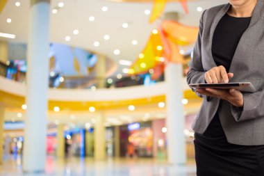 Alışveriş merkezinde dijital tablet kullanarak iş kadını.