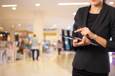 Alışveriş merkezinde dijital tablet kullanarak iş kadını.