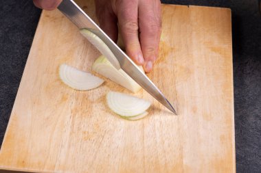 Erkek eller doğrama tahtasıyla soğan doğruyor.