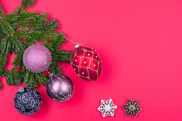 Weihnachtsschmuck, Tannenzweige auf rotem Hintergrund. — Stockfoto