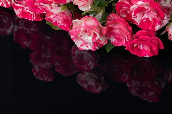 黑色背景上的一束玫瑰 其表面闪烁着花朵的倒影 — 图库照片