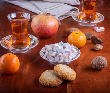 Meyve, fındık ve kurabiyelerle dolu bir masada çay ve Türk lokumu.