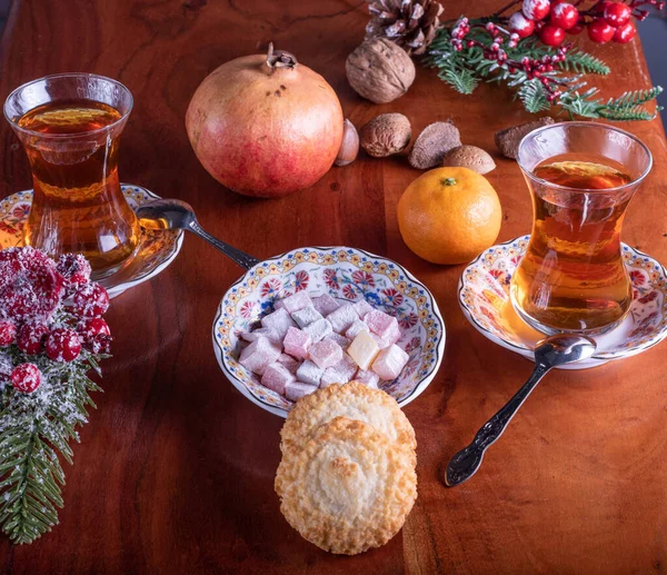 Meyve, fındık ve kurabiyelerle dolu bir masada çay ve Türk lokumu.