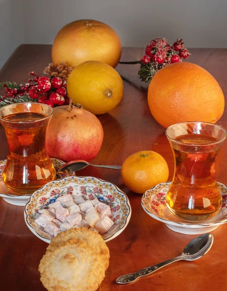 Meyve, fındık ve kurabiyelerle dolu bir masada çay ve Türk lokumu.